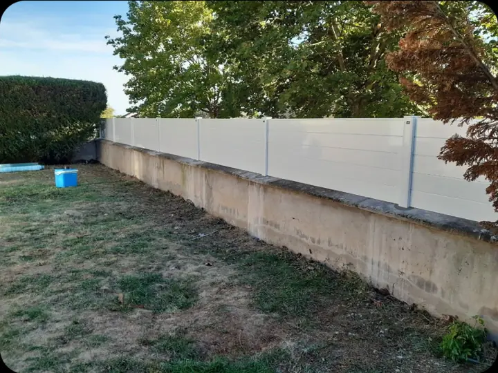 Clôture blanche posée sur un muret de jardin
